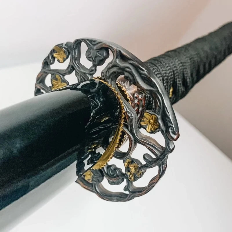 Close-up of an ornate katana guard and black scabbard