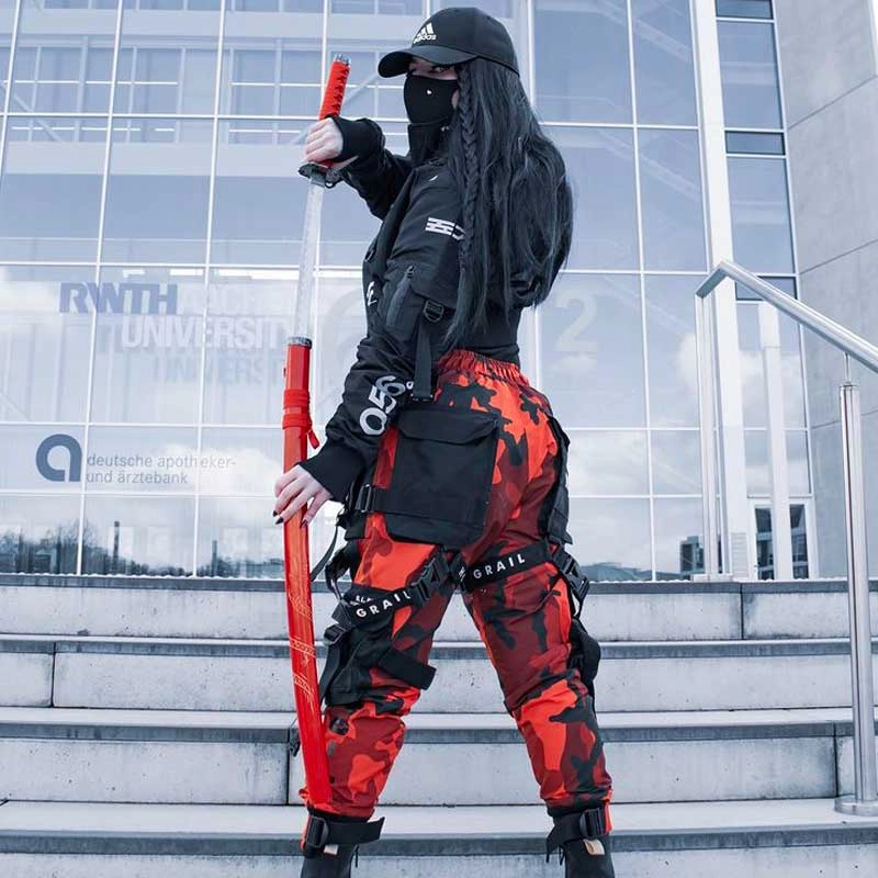 A person in a black jacket holding a red katana on city steps