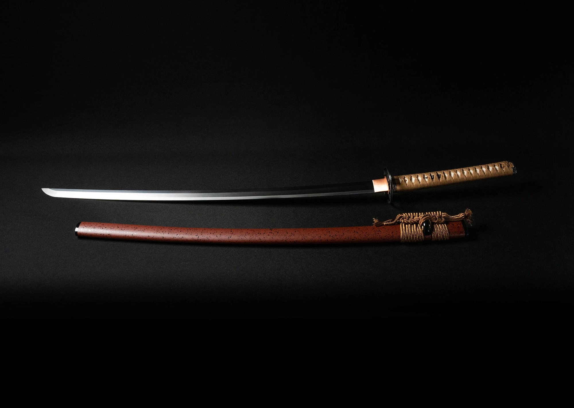 A long katana and its scabbard lying side by side on black